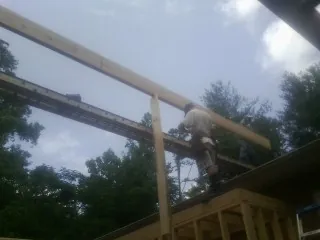 Carpenter setting a ridge beam over a new addition frame — Ice Dam Removal by Roofing Brothers in Wellborn