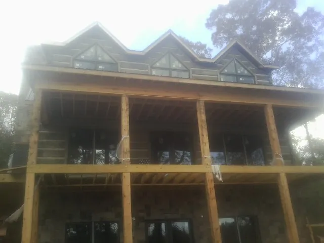 Dormers and porch framing on a large log home under construction — Roof Coating work by our crew in Wellborn