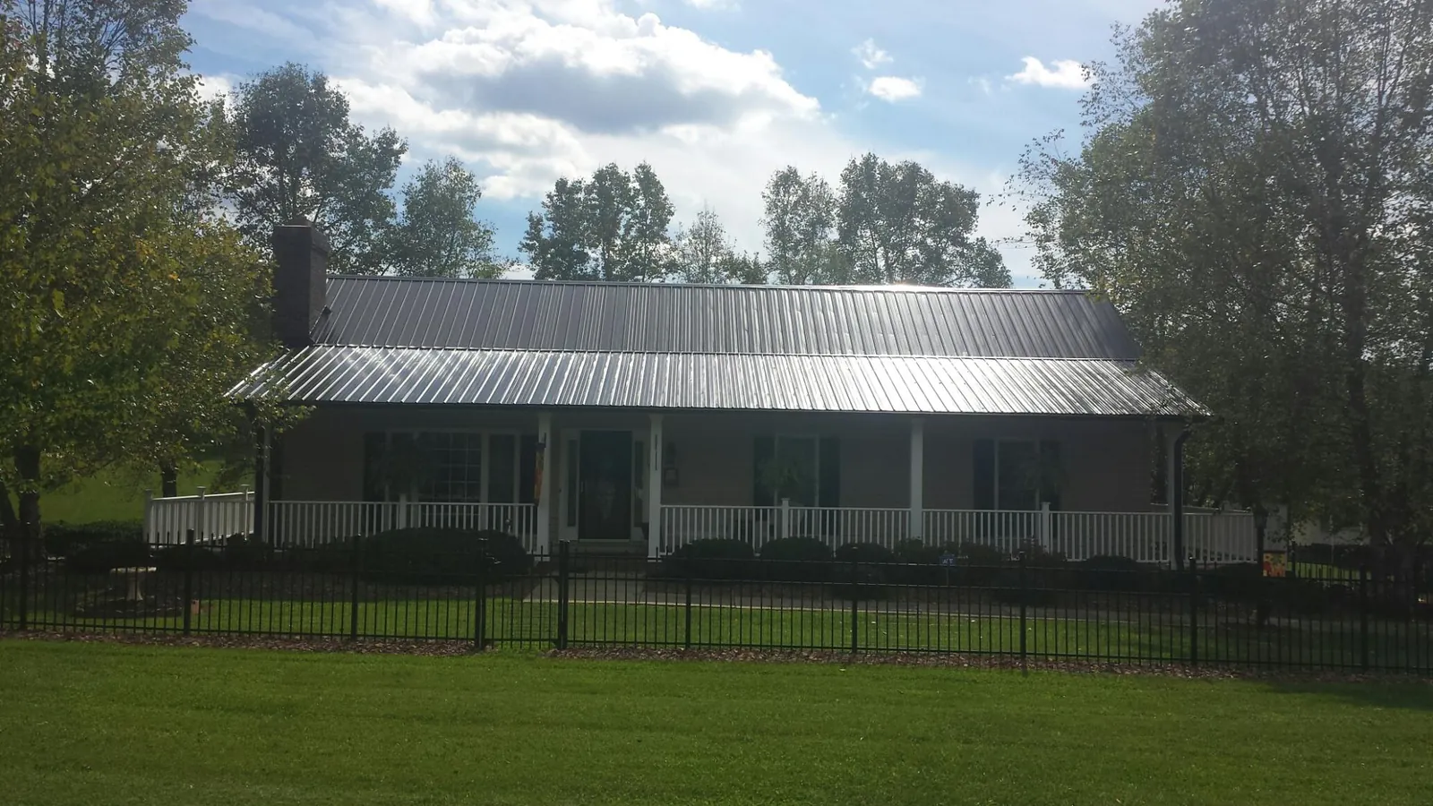 Gray metal roof on a brick ranch with a full width front porch — Gutter Guard Installation work by our crew in Wellborn